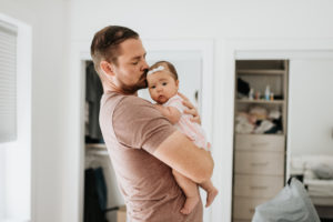 Father comforting baby girl in arms at home Father comforting baby girl in arms at home